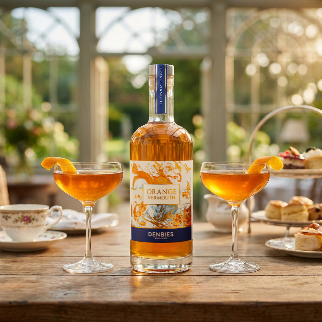 Orange Vermouth bottle served with two saucer glasses with an orange peel in a tea and cake party setting