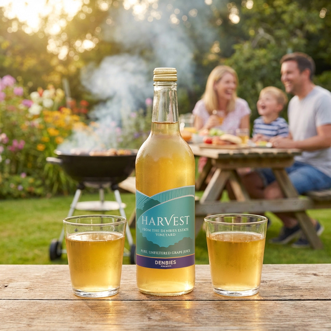 Harvest Grape Juice bottle served with two glasses in a garden bbq setting with family