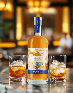 Denbies Orange Vermouth bottle with two glasses of orange cocktail on a bar counter.