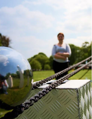 Person standing behind a reflective surface with a scenic background